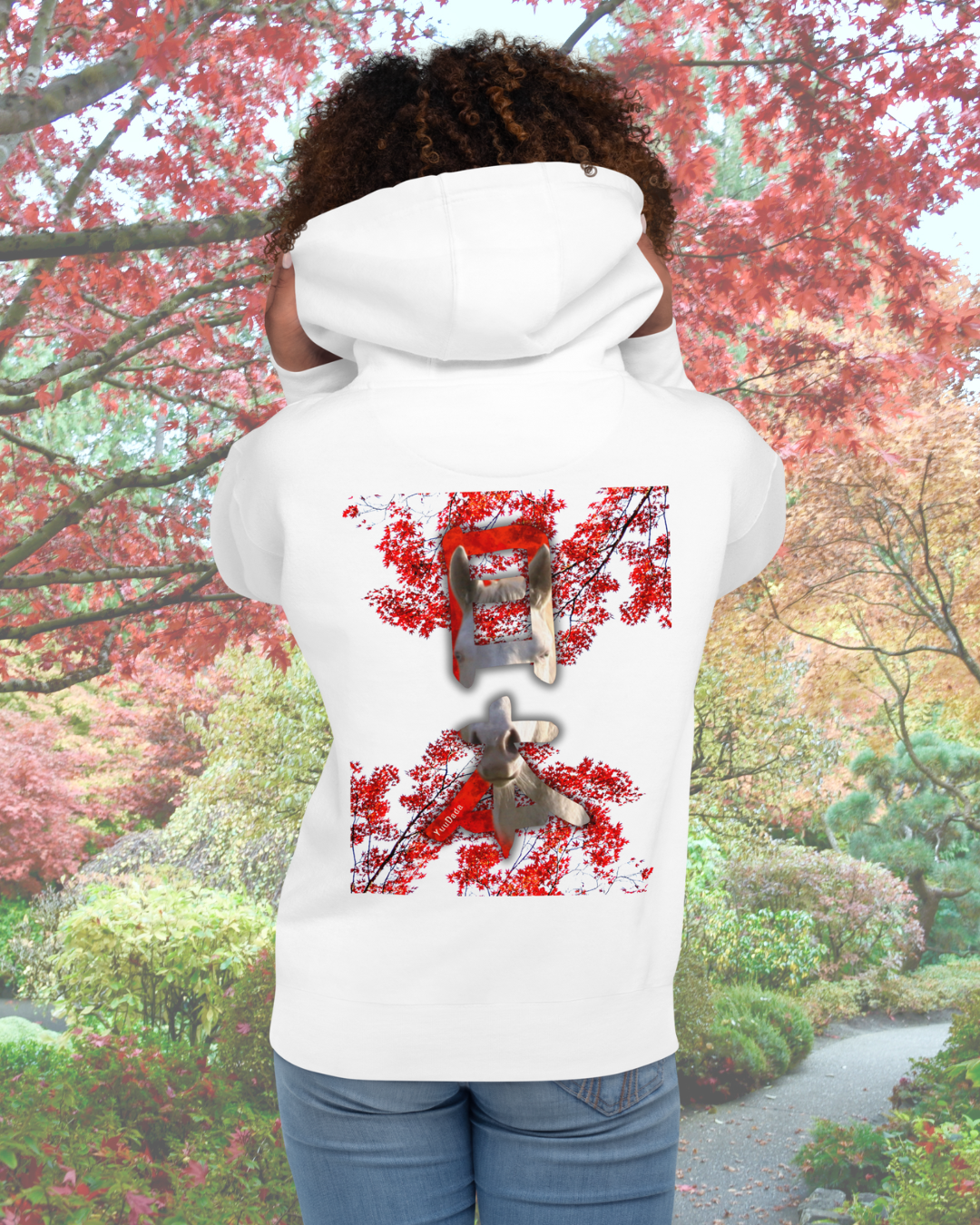 Femme de dos portant un hoodie blanc avec un motif kanji japonais devant un érable rouge dans un jardin japonais