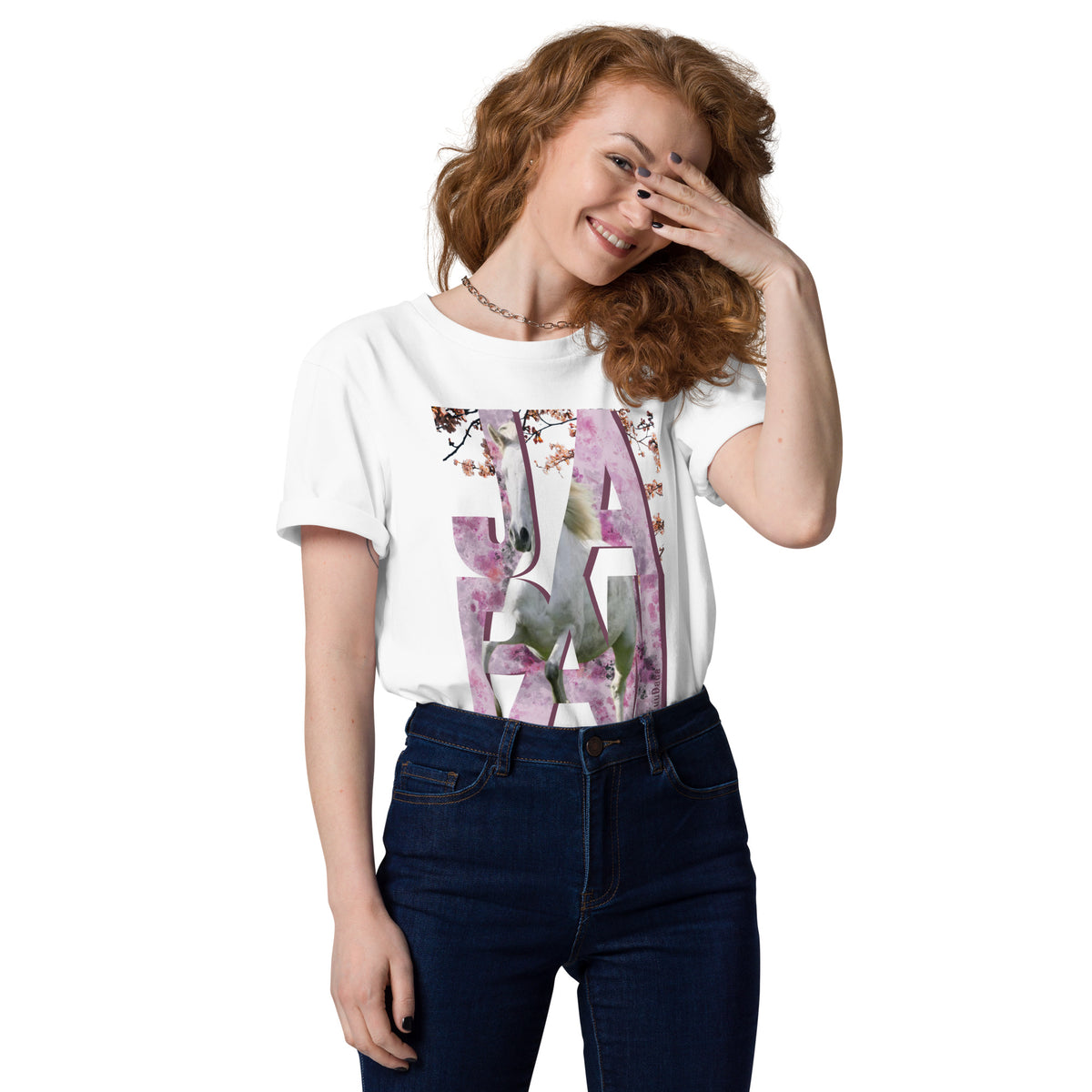 Femme souriante portant un t-shirt blanc orné d’un visuel rose avec des lettres "JAPAN" et un cheval intégré dans le design – collection YuuDada