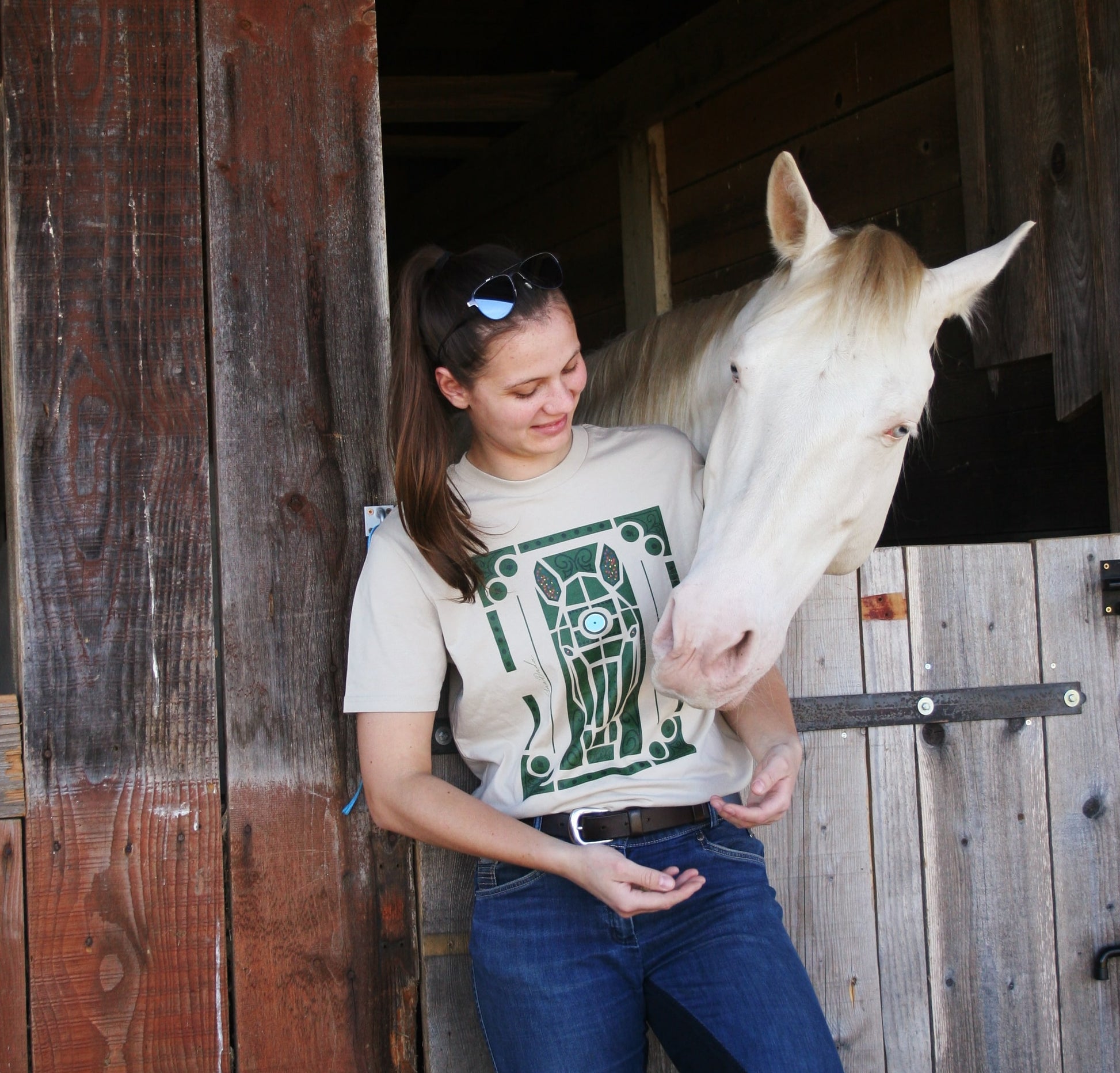 Tshirt beige avec motif de cheval dans les jardins de Versailles, porté par une cavalière avec son cheval à côté d'elle