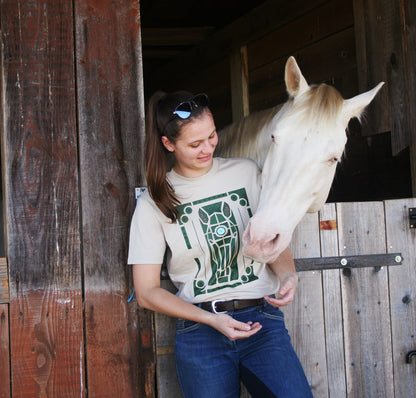 Tshirt beige avec motif de cheval dans les jardins de Versailles, porté par une cavalière avec son cheval à côté d'elle
