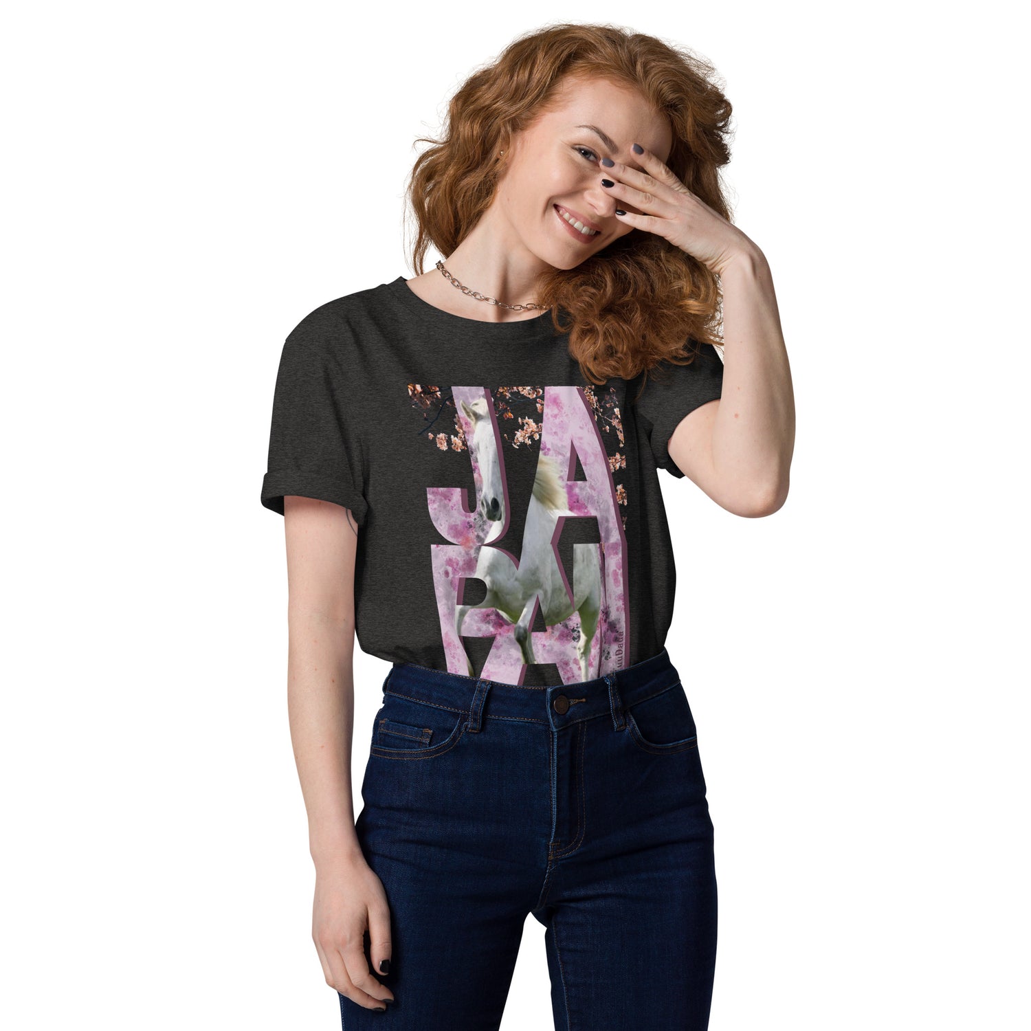 Femme souriante portant un t-shirt gris orné d’un visuel rose avec des lettres "JAPAN" et un cheval intégré dans le design – collection YuuDada