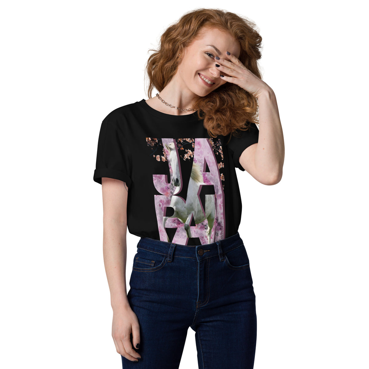 Femme souriante portant un t-shirt noir orné d’un visuel rose avec des lettres "JAPAN" et un cheval intégré dans le design – collection YuuDada